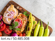 Chicken steak placed on a wooden tray with bell peppers, tomatoes, red onions, pineapple sauce, lettuce, and sesame seeds. Стоковое фото, агентство Ingram Publishing / Фотобанк Лори