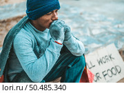 a man sitting beggars with homeless please help message. Selective focus. Стоковое фото, агентство Ingram Publishing / Фотобанк Лори
