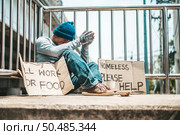 The man sitting begging on an overpass with messages homeless people please help and work well with food. Стоковое фото, агентство Ingram Publishing / Фотобанк Лори