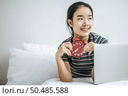 That woman sat on the bed, held the alarm clock and placed the laptop. Стоковое фото, агентство Ingram Publishing / Фотобанк Лори