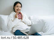 That woman sat on the bed, held the alarm clock and placed the laptop. Стоковое фото, агентство Ingram Publishing / Фотобанк Лори