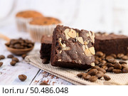 Chocolate brownies on sackcloth and coffee beans on a wooden table. Selective focus. Стоковое фото, агентство Ingram Publishing / Фотобанк Лори