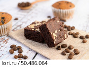 Chocolate brownies on sackcloth and coffee beans on a wooden table. Selective focus. Стоковое фото, агентство Ingram Publishing / Фотобанк Лори
