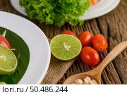 Thai style spicy food, Som Tum food concept, props decoration Garlic, lemon, peanuts, tomatoes, and salad on wood table. Стоковое фото, агентство Ingram Publishing / Фотобанк Лори