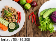 Spicy Minced Pork Salad on a white plate on wooden table. Top view. Стоковое фото, агентство Ingram Publishing / Фотобанк Лори