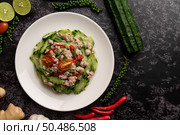 Stir fried zucchini with minced pork in white plate, and spices on a black cement floor. Стоковое фото, агентство Ingram Publishing / Фотобанк Лори