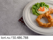 Freshly baked soft pretzel with generous sprinkling of coarse salt and sesame on white dish, decorate with lettuce and carrot beautifully, copy space. Стоковое фото, агентство Ingram Publishing / Фотобанк Лори