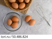 Top View three eggs in glasses bowl, blurred eggs in wicker basket and egg beater on the floor, preparing preparing for cooking food or dessert, copy space . Стоковое фото, агентство Ingram Publishing / Фотобанк Лори