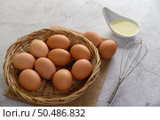 Selective focus eggs on sack cloth, many eggs on wicker basket and glasses bowl, oil and egg whisk placed on the floor, preparing for cooking food or dessert, copy space. Стоковое фото, агентство Ingram Publishing / Фотобанк Лори
