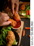 Two hand holding crispy fried chicken dipped in tomato sauce.Selective focus. Стоковое фото, агентство Ingram Publishing / Фотобанк Лори