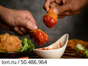 Two hand holding crispy fried chicken dipped in tomato sauce.Selective focus. Стоковое фото, агентство Ingram Publishing / Фотобанк Лори