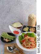 Thai papaya salad in a white plate with Sticky rice, dried shrimp, Spoon, and fork. Стоковое фото, агентство Ingram Publishing / Фотобанк Лори