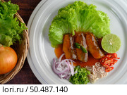 Top View Spicy salad of sardine with tomato sauce arranged nicely in white dish and ingredient herb for cooking put in a wicker basket on wooden table, copy space. Стоковое фото, агентство Ingram Publishing / Фотобанк Лори