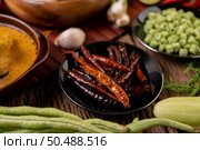 Dried chilies fried in a black plate with lentils. Cucumbers and garlic are placed on the wooden table. Стоковое фото, агентство Ingram Publishing / Фотобанк Лори