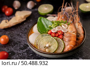 Tom Yum Kung in a bowl with tomato, chili, lemongrass, garlic, lemon, and kaffir lime leaves. Стоковое фото, агентство Ingram Publishing / Фотобанк Лори