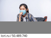 An uncomfortable woman sitting on a chair and wearing a mask. Стоковое фото, агентство Ingram Publishing / Фотобанк Лори