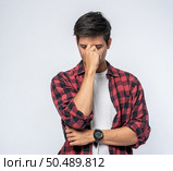 A man with a migraine headache holding her hand in her nose. Стоковое фото, агентство Ingram Publishing / Фотобанк Лори