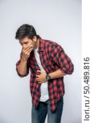 A man standing with a stomachache Put your hands on your stomach and cover your mouth. Стоковое фото, агентство Ingram Publishing / Фотобанк Лори