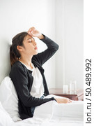 An uncomfortable woman sits on the bed and has medicine on the table. Стоковое фото, агентство Ingram Publishing / Фотобанк Лори