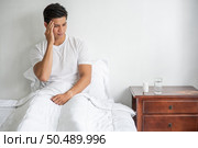 Migraine man, hand touching head, sitting in bed. Стоковое фото, агентство Ingram Publishing / Фотобанк Лори