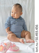 A baby learns to sit on a white bed. Стоковое фото, агентство Ingram Publishing / Фотобанк Лори