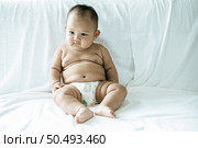 A baby learns to sit on a white bed. Стоковое фото, агентство Ingram Publishing / Фотобанк Лори