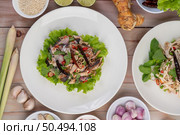 Deep-fried mackerel topped with galangal, pepper, mint, red onions in a white dish with a variety of vegetables. Стоковое фото, агентство Ingram Publishing / Фотобанк Лори