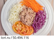 Tuna salad with carrots, tomatoes, cabbage on a white plate on a wooden floor. Стоковое фото, агентство Ingram Publishing / Фотобанк Лори