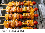 BBQ grill with a variety of meats, complete with tomatoes and bell peppers. Стоковое фото, агентство Ingram Publishing / Фотобанк Лори