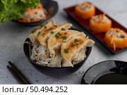 Gyoza in a black cup with a cup of sauce. Стоковое фото, агентство Ingram Publishing / Фотобанк Лори