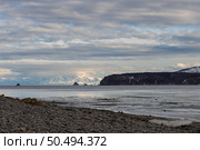 Бухта Гертнера, Охотское море, Магаданская область, Россия. Красивый вечерний морской пейзаж. Вид с каменистого берега на морскую бухту. Вдали скалистые острова и горы. Облачная погода. Природа Дальнего Востока России. Стоковое фото, фотограф Андрей Степанов / Фотобанк Лори