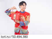 Man wear Cheongsam ready to give red bag to sister for surprising in traditional day. Стоковое фото, агентство Ingram Publishing / Фотобанк Лори