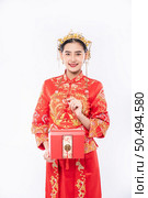 Woman wear Cheongsam suit ready to give red bag to sister for surprising in traditional day. Стоковое фото, агентство Ingram Publishing / Фотобанк Лори