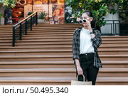 Portrait of young Asian woman wearing eyeglasses going down stairs with shopping paper bag. she smile and looking at camera,  Lifestyle and shopping concept, Shopping selection. Стоковое фото, агентство Ingram Publishing / Фотобанк Лори