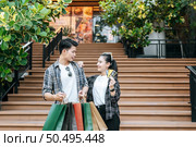 Smiley Young couple holding multiple paper shopping bag going down stairs of large shopping mall and pretty woman show credit card in hand,  Lifestyle and shopping concept, copy space. Стоковое фото, агентство Ingram Publishing / Фотобанк Лори