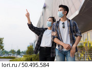 Asian Young Couple in protection mask standing outdoor of large building, They are discussion with happiness, New normal lifestyle amid coronavirus outbreak. Стоковое фото, агентство Ingram Publishing / Фотобанк Лори