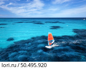 Aerial view of windsurfer on blue sea at sunny summer day. Windsurfing. Extreme sport and vacation. Top view of man on windsurfer board, waves, clear azure water in Sardinia, Italy. Tropical landscape. Стоковое фото, агентство Ingram Publishing / Фотобанк Лори