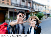 selective focus hands of young backpacker couple in protection face mask and sunglasses keep distance raise palms express negative attitude coronavirus don’t close contact while travel in city street. Стоковое фото, агентство Ingram Publishing / Фотобанк Лори