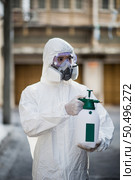 Disinfection specialist man in personal protective equipment (ppe) suit, gloves, mask and face shield, cleaning Quarantine area with a bottle of pressurized spray disinfectant to remove coronavirus. Стоковое фото, агентство Ingram Publishing / Фотобанк Лори