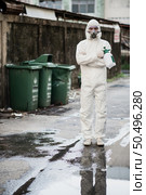 Disinfection specialist man in personal protective equipment (ppe) suit, gloves, mask and face shield, cleaning Quarantine area with a bottle of pressurized spray disinfectant to remove coronavirus. Стоковое фото, агентство Ingram Publishing / Фотобанк Лори