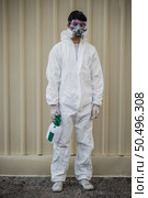 Portrait Disinfection specialist man in PPE suit, gloves, mask and face shield performing public decontamination, standing and holding bottle for spray disinfectant to remove covid-19  . Стоковое фото, агентство Ingram Publishing / Фотобанк Лори