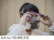 Man in personal protective equipment (PPE) suit wearing clear glasses and protective gas mask preparing to remove covid-19. Стоковое фото, агентство Ingram Publishing / Фотобанк Лори