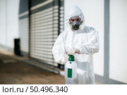 Disinfection specialist staff in personal protective equipment (ppe) suit, gloves, mask and face shield, cleaning Quarantine area with a bottle of pressurized spray disinfectant to remove covid-19. Стоковое фото, агентство Ingram Publishing / Фотобанк Лори