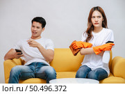 Asian young couple quarrels while cleaning in the living room, Young woman wearing gloves and holding spray bottle in hand with feel dissatisfied her husband, family issues and relationship concept. Стоковое фото, агентство Ingram Publishing / Фотобанк Лори