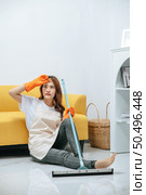 Young housekeeper woman sitting near sofa in living room with feel tired, She wipe sweat and take a break after finishing cleaning the house, copy space. Стоковое фото, агентство Ingram Publishing / Фотобанк Лори