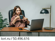 Portrait of smiling happy beautiful asian woman relaxing with hot coffee, She using technology of laptop computer to working from home during self-isolation and quarantine covid-19 coronavirus outbreak. Стоковое фото, агентство Ingram Publishing / Фотобанк Лори