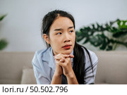 Depressed woman sitting on sofa at home, thinking about important things or feels unhappy with problem in personal life, copy space. Стоковое фото, агентство Ingram Publishing / Фотобанк Лори