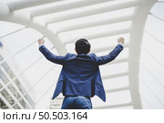Successfully of young businessman keeping arms raised and expressing positivity while standing outdoors . Стоковое фото, агентство Ingram Publishing / Фотобанк Лори