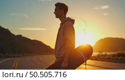 Young hipster man holds cool longboard in hand. Sun sunset light leak in lens. Beautiful travel wanderlust concept. Millennial adventure trip. Skater walk. Стоковое AI-видео, аниматор Sergey Grishin / Фотобанк Лори
