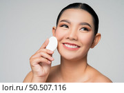 Portrait of Beautiful Asian woman holding foundation or cushion sponge puff. Skin care healthy hair and skin close up face beauty isolated over background. Cosmetology and Spa concept. Стоковое фото, агентство Ingram Publishing / Фотобанк Лори